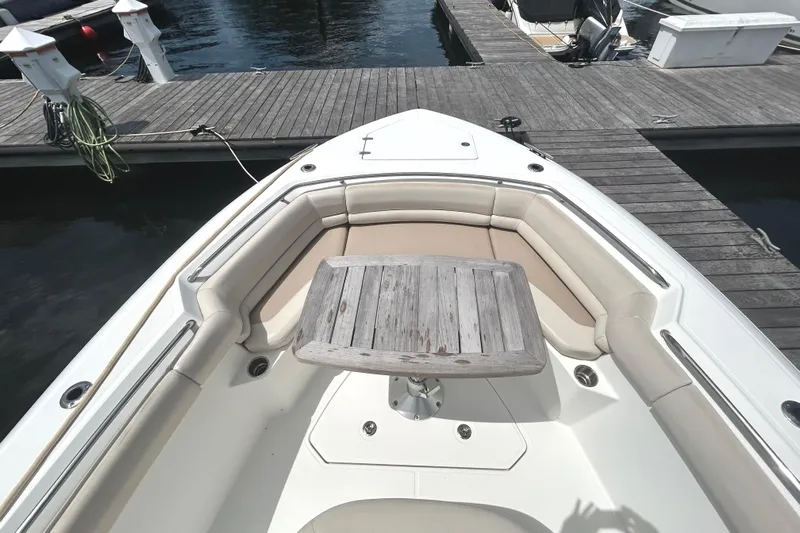  Yacht Photos Pics 2017 Boston Whaler 330 Outrage boat with cushioned seating and wooden table at dock.
