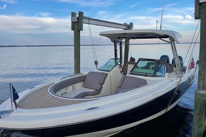  Yacht Photos Pics 2019 Chris-Craft Calypso 26 boat docked by calm waters under a blue sky.