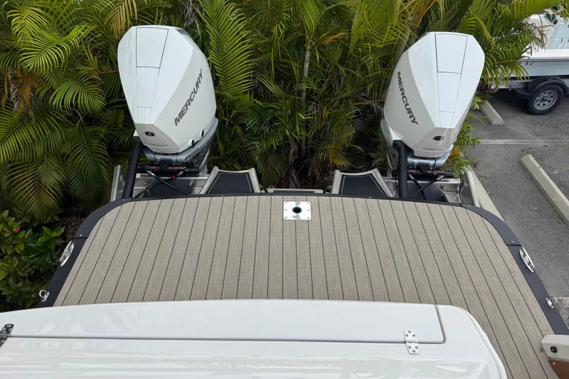  Yacht Photos Pics 2026 Avalon Excalibur 27' boat with dual Mercury outboard motors, surrounded by lush greenery.