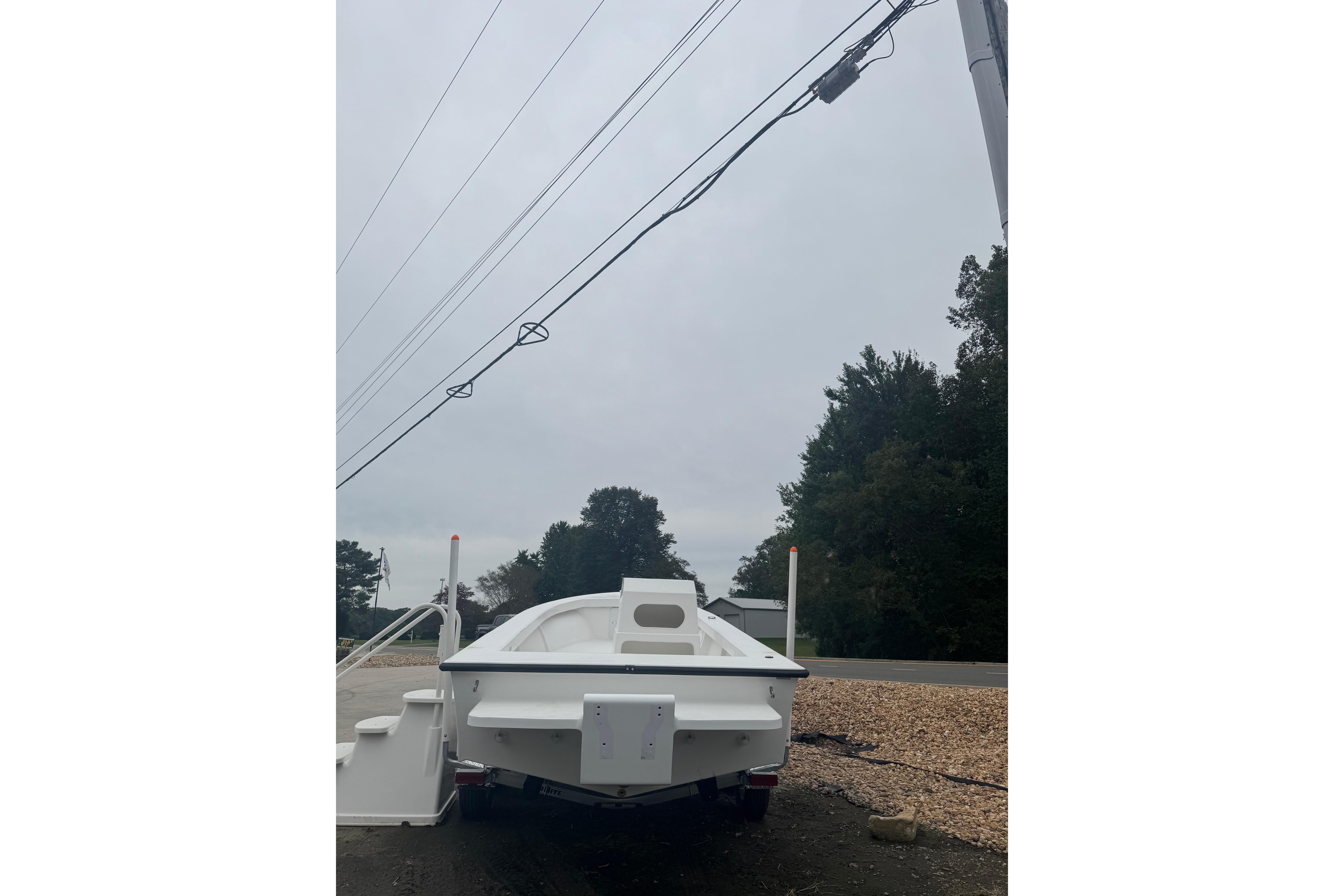 2026 C-Hawk 23 Center Console boat on trailer, parked near road and trees.