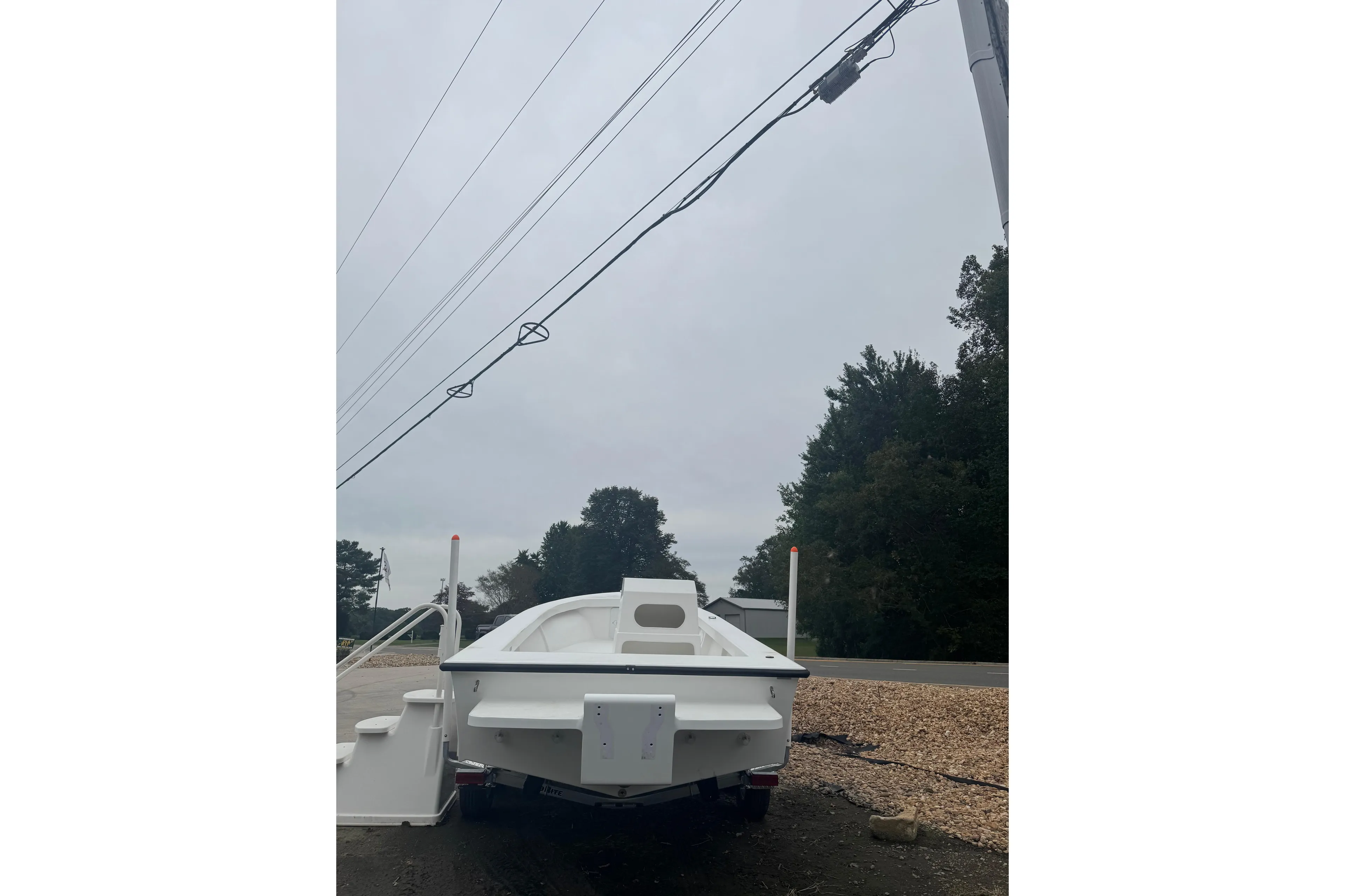 2026 C-Hawk 23 Center Console boat on trailer, parked near road and trees.