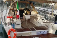 2015 Dufour 382 Grand Large sailboat docked at marina with scenic mountain backdrop.