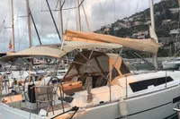 2015 Dufour 382 Grand Large sailboat docked in marina, with scenic hillside backdrop.
