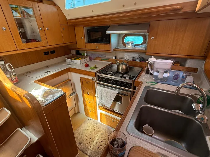  Yacht Photos Pics 2005 Catalina 470 yacht kitchen with wooden cabinets, stove, and double sink.