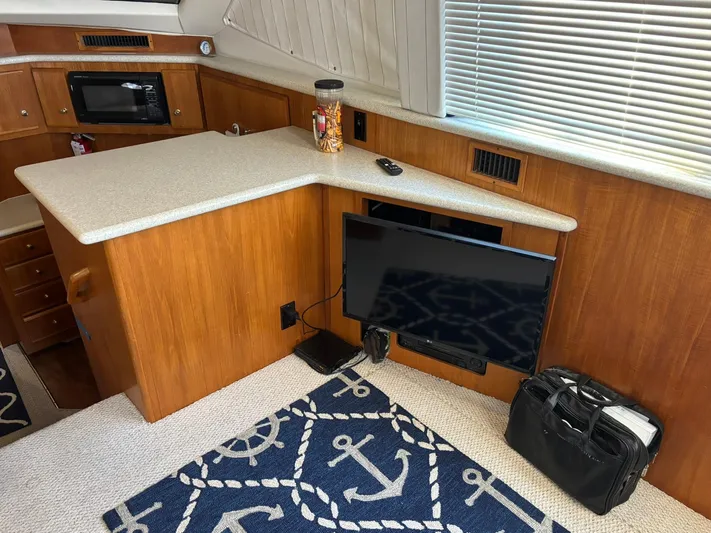 Musketeer Yacht Photos Pics Interior of 2000 Carver 406 Yacht with TV, counter, and nautical-themed rug.