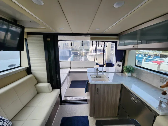 Foxyot Yacht Photos Pics Luxurious interior of 2022 Regal 38 Grande Coupe yacht with modern kitchen and seating area.