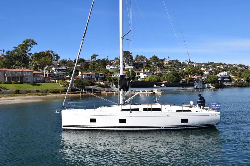 Hanse 418 #303 San Yacht Photos Pics 2023 Hanse 418 sailboat on calm water near a coastal town.