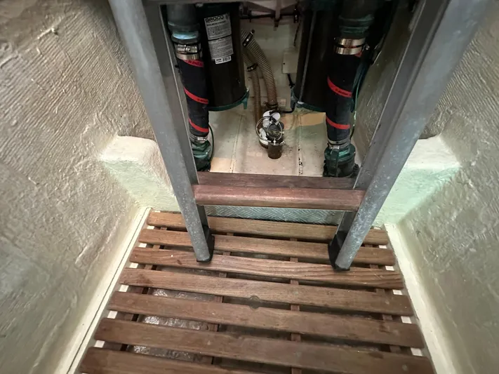 Vivacious Yacht Photos Pics Engine compartment of 2002 Grand Banks Eastbay 43 with visible pipes and wooden flooring.