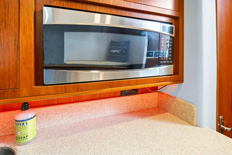 "double Down" Yacht Photos Pics Built-in microwave in wooden cabinet, beige countertop, and soap bottle.
