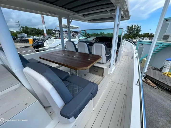  Yacht Photos Pics 2018 Axopar 37 Sun Top boat with spacious seating and wooden table on deck.