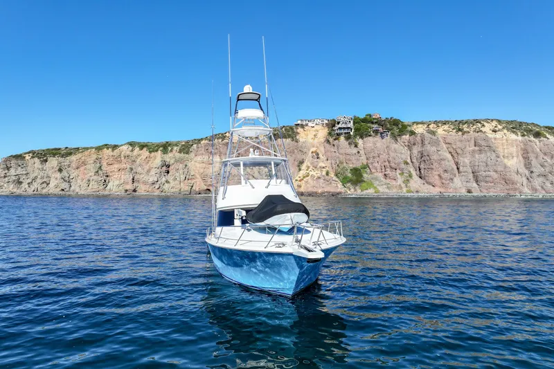 Trouble Maker Yacht Photos Pics 2013 Viking 46 Convertible yacht on calm sea with rocky cliff background.