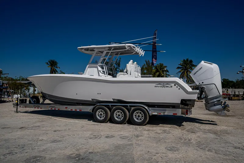  Yacht Photos Pics 2025 Invincible 33 Open Fisherman boat on trailer, parked outdoors under clear blue sky.