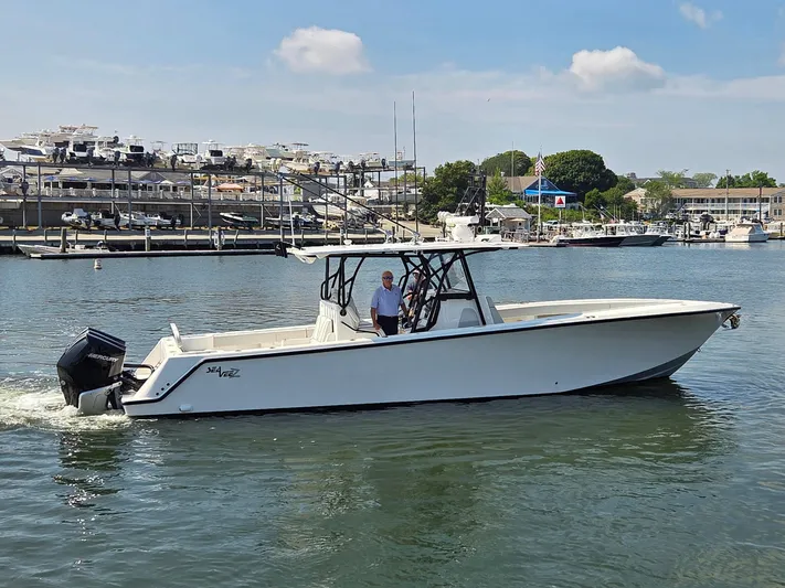  Yacht Photos Pics 2023 SeaVee 37 Z boat cruising in a marina with docked yachts in the background.