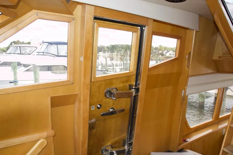  Yacht Photos Pics Interior view of 2002 McKinna 57 Pilothouse yacht with wooden finish and marina backdrop.