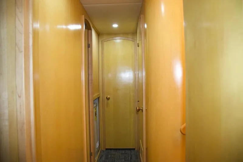 Yacht Photos Pics Narrow hallway inside 2002 McKinna 57 Pilothouse yacht with wooden paneling and carpeted floor.