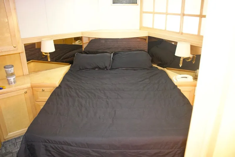  Yacht Photos Pics Luxurious bedroom in 2002 McKinna 57 Pilothouse yacht with black bedding and wooden cabinetry.