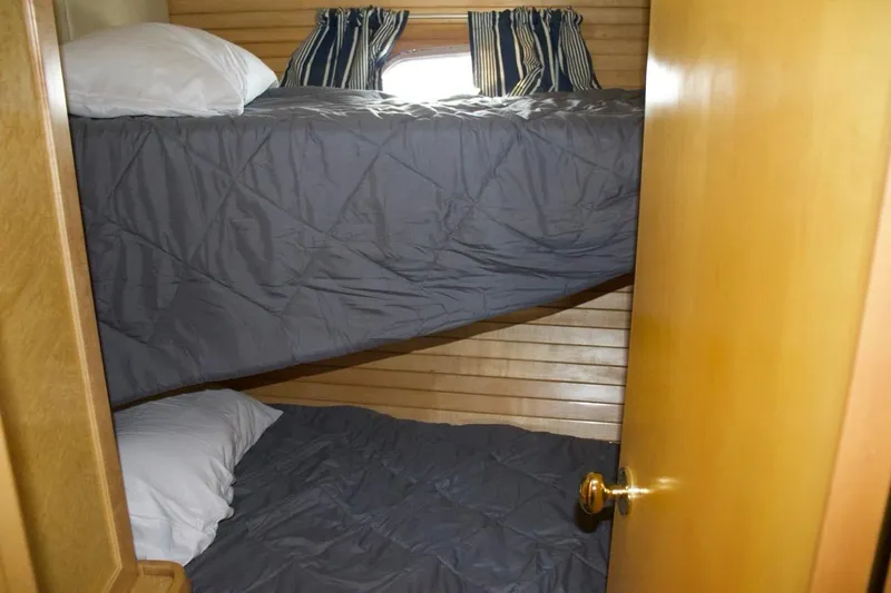  Yacht Photos Pics Bunk beds in 2002 McKinna 57 Pilothouse cabin with wooden paneling and striped curtains.