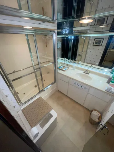 Gentle Ben Yacht Photos Pics Luxurious bathroom in 1989 Hatteras 80 Cockpit Motor Yacht with mirrored cabinets and bathtub.