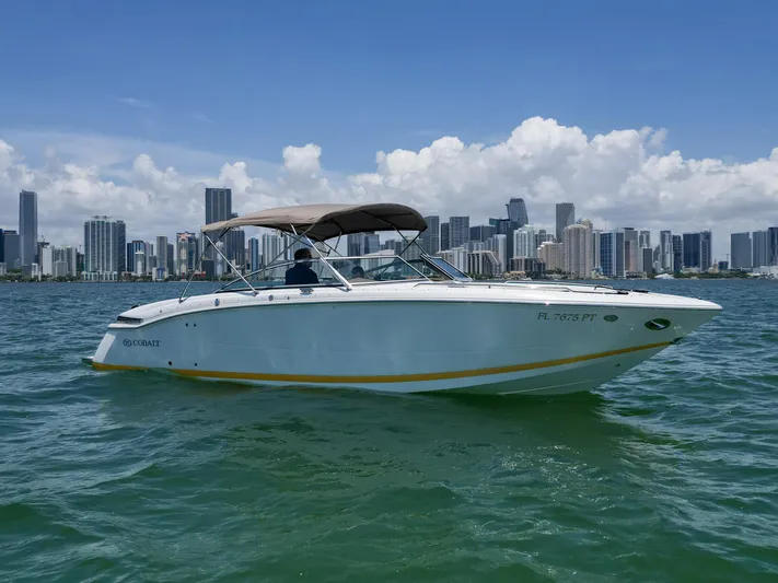  Yacht Photos Pics 2013 Cobalt 296 boat cruising near city skyline on a sunny day.