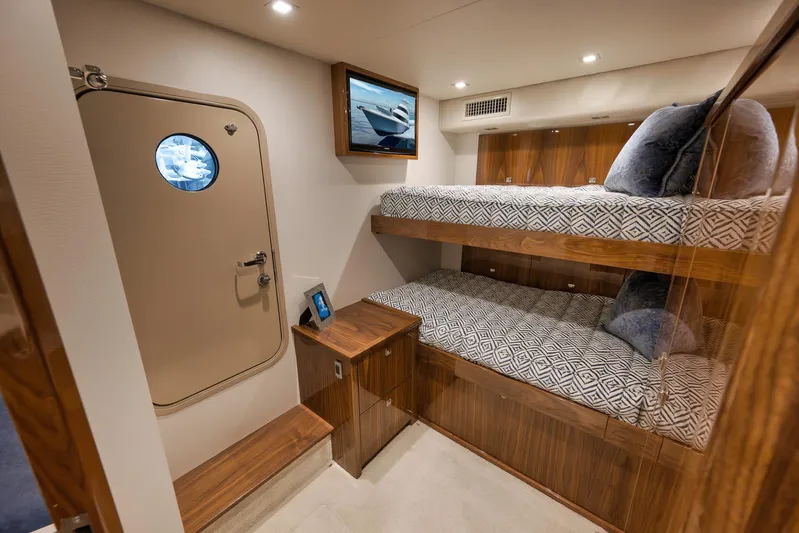 Makara Yacht Photos Pics Cabin interior of 2018 Viking 72 Sky Bridge yacht with bunk beds and wooden accents.