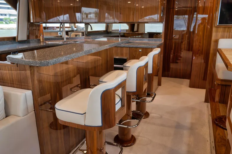 Makara Yacht Photos Pics Luxurious interior of 2018 Viking 72 Sky Bridge yacht with elegant bar seating and wood finishes.