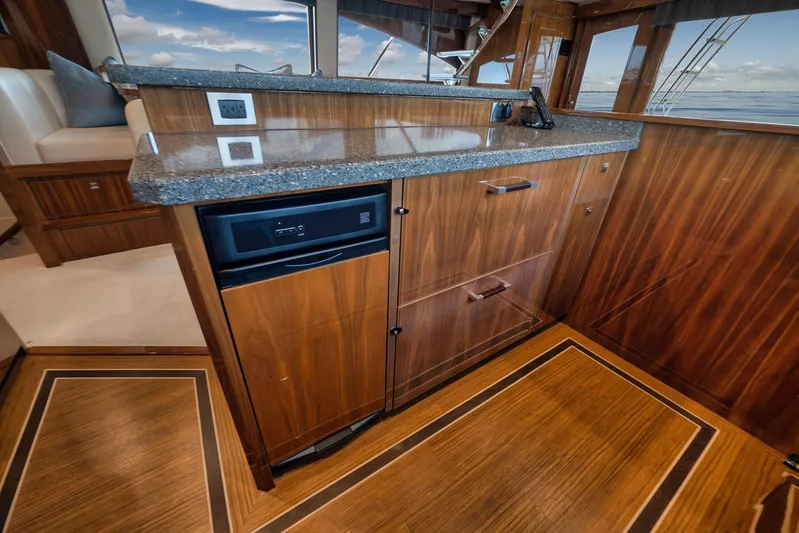 Makara Yacht Photos Pics Luxurious interior of 2018 Viking 72 Sky Bridge yacht with elegant wood cabinetry and granite countertop.