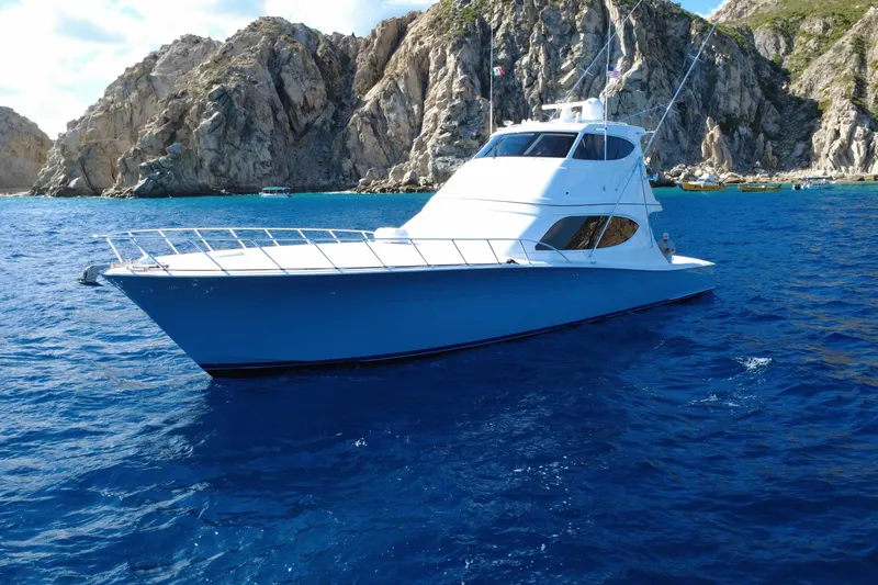 Sixpack Yacht Photos Pics 2013 Hatteras GT63 yacht cruising in clear blue waters near rocky cliffs.