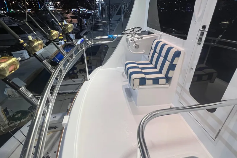 Sixpack Yacht Photos Pics 2013 Hatteras GT63 yacht deck with striped seating and fishing rods at night.