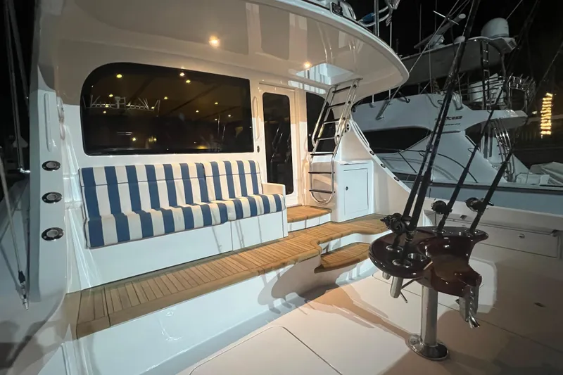 Sixpack Yacht Photos Pics 2013 Hatteras GT63 yacht deck with striped seating and fishing rods at night.