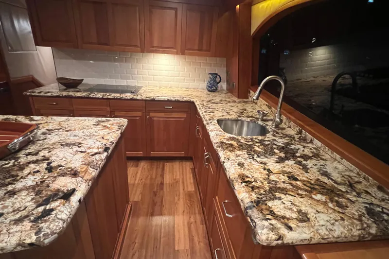 Sixpack Yacht Photos Pics Luxurious kitchen interior of 2013 Hatteras GT63 yacht with granite countertops and wooden cabinetry.