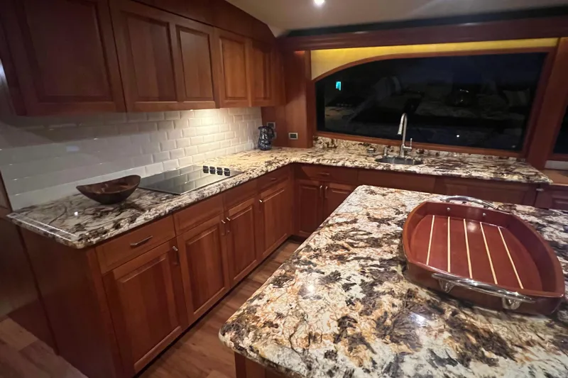 Sixpack Yacht Photos Pics Luxurious kitchen interior of 2013 Hatteras GT63 yacht with granite countertops and wooden cabinetry.