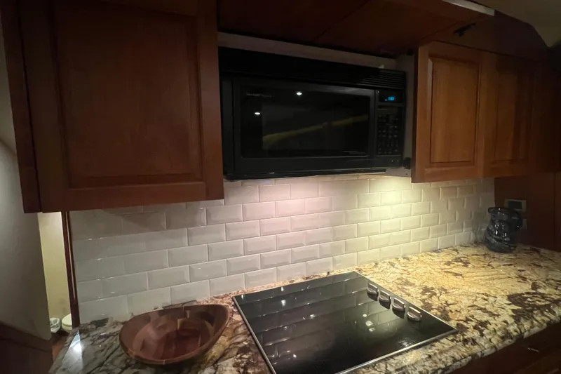 Sixpack Yacht Photos Pics 2013 Hatteras GT63 yacht kitchen with granite countertop, microwave, and electric stove.