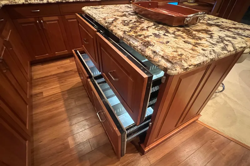 Sixpack Yacht Photos Pics Luxury yacht kitchen with granite countertop and wooden cabinetry, featuring open pull-out drawers.