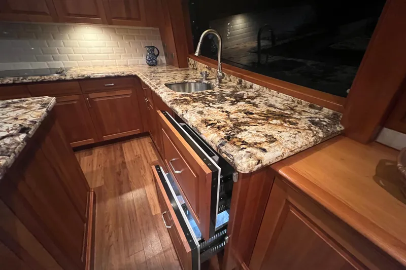 Sixpack Yacht Photos Pics Luxurious kitchen interior of 2013 Hatteras GT63 yacht with granite countertops and wooden cabinetry.