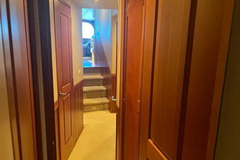 Sixpack Yacht Photos Pics Interior hallway of 2013 Hatteras GT63 yacht with wooden doors and carpeted stairs.