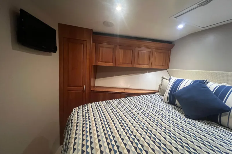 Sixpack Yacht Photos Pics Cozy bedroom in 2013 Hatteras GT63 yacht with striped bedding and wooden cabinetry.