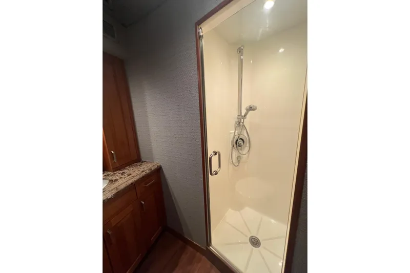Sixpack Yacht Photos Pics Shower area in 2013 Hatteras GT63 yacht with wooden cabinetry and granite countertop.