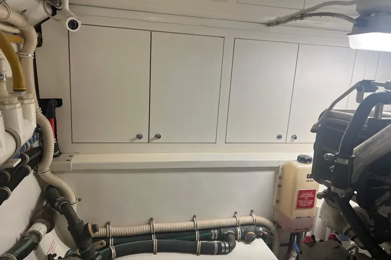 Sixpack Yacht Photos Pics Engine room of a 2013 Hatteras GT63 yacht with visible pipes and storage cabinets.