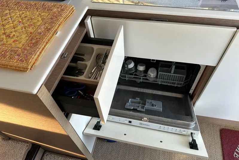 Lola Yacht Photos Pics Compact kitchen with open dishwasher and utensil drawer in a 2019 Prestige 460 yacht.