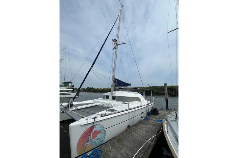 Namaste Yacht Photos Pics 2004 Lagoon 380 catamaran docked, featuring a colorful wave design on the hull.