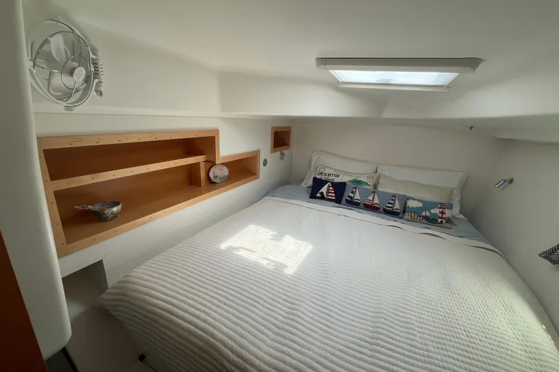 Namaste Yacht Photos Pics Cozy bedroom in 2004 Lagoon 380 catamaran with nautical-themed pillows and wooden shelves.