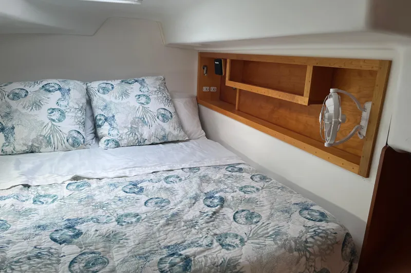 Namaste Yacht Photos Pics Cozy cabin interior of 2004 Lagoon 380 with floral bedding and wooden shelving.