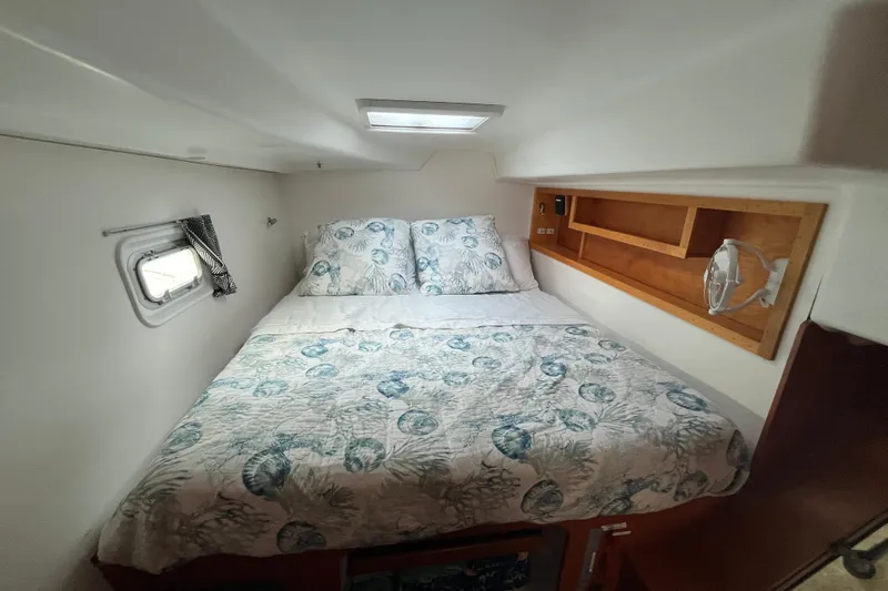 Namaste Yacht Photos Pics Cozy cabin interior of 2004 Lagoon 380 catamaran with patterned bedding and wooden shelving.