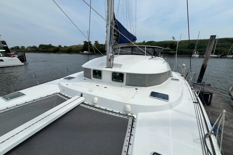 Namaste Yacht Photos Pics 2004 Lagoon 380 catamaran docked by a serene river, showcasing its spacious deck.