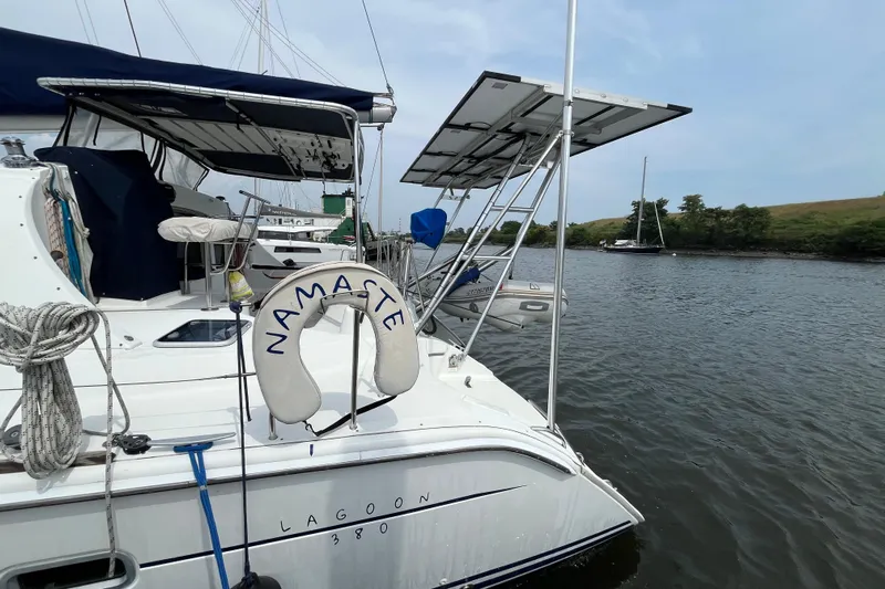 Namaste Yacht Photos Pics 2004 Lagoon 380 catamaran with solar panels and "Namaste" life ring on a calm river.
