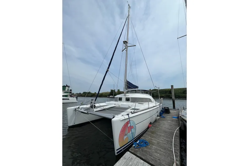 Namaste Yacht Photos Pics 2004 Lagoon 380 catamaran docked, featuring a colorful hull design and clear sky backdrop.