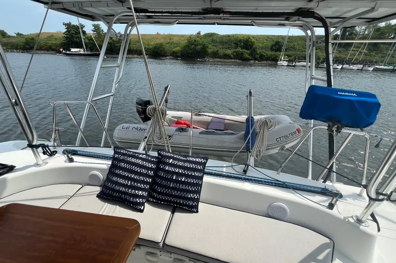 Namaste Yacht Photos Pics Lagoon 380 catamaran deck with cushions, table, and dinghy on calm water.