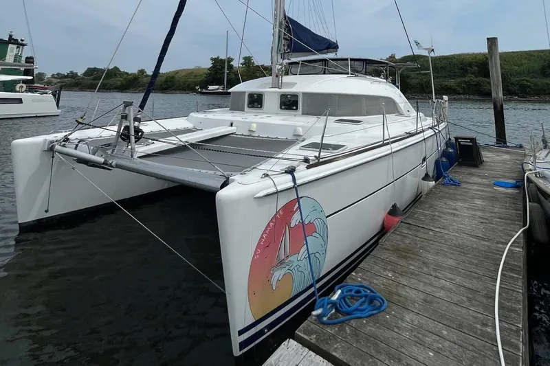Namaste Yacht Photos Pics 2004 Lagoon 380 catamaran docked, featuring a colorful wave design on the hull.