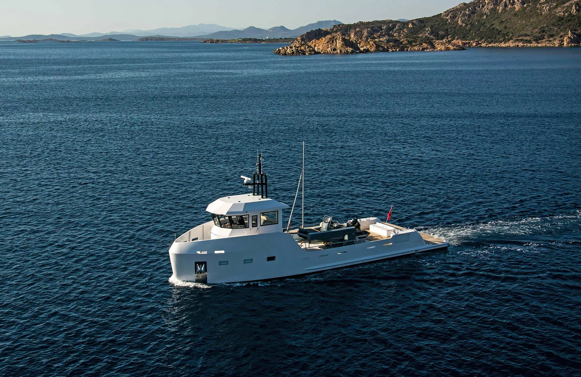 2027 Outer Reef Yachts 20 YXT cruising on open sea near rocky coastline.