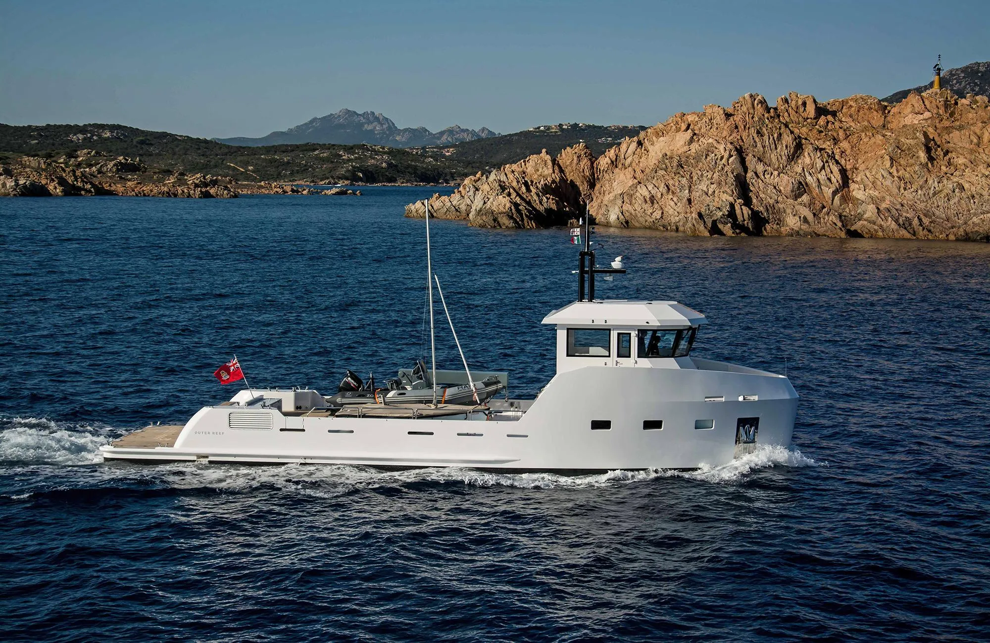 Outer Reef Yachts 20 YXT 2027 cruising near rocky coastline.